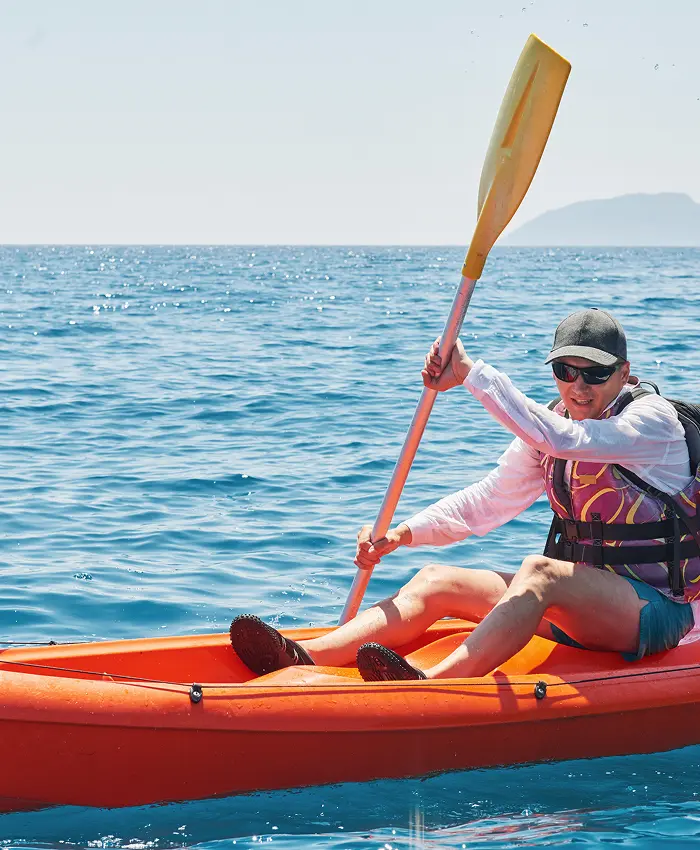 Man kayaking in the ocean holding a paddle